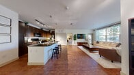 Located at 3310 S Kenton St in Denver, CO, this thoughtfully designed 2-bedroom, 2-bathroom residence offers a comfortable and functional single-floor layout. The open-concept living and kitchen area forms the heart of the home, where rich hardwood-style flooring flows seamlessly throughout. The kitchen is outfitted with dark espresso cabinetry, granite countertops, stainless steel appliances including a refrigerator, and a peninsula island with bar seating illuminated by pendant lighting and a track lighting system above. The living room receives generous natural light through large windows overlooking lush outdoor greenery, creating a bright and welcoming ambiance with access to an exterior door. Both bedrooms feature plush carpeting and a calm, neutral palette, with the primary bedroom offering notable space and a dedicated closet. Each bathroom is finished with dark wood vanities, granite countertops, tile flooring, and tub-shower combinations. Three closets provide ample storage throughout, and an in-unit laundry area adds everyday convenience. A connecting hallway ties the layout together efficiently, making this residence as practical as it is comfortable.