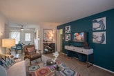 Located at 5109 Goldsboro in Hampton, Virginia, this single-floor residence offers a well-designed layout that balances comfort and style throughout. The open-concept living area is generously proportioned, featuring plush carpeting, a striking teal accent wall, and abundant natural light from multiple windows. The space flows seamlessly into a dedicated dining area, which is bright and welcoming with direct access to an exterior door and large windows that bring in natural light.

The kitchen is equipped with warm wood cabinetry, dark granite-style countertops, hardwood-style flooring, and a full suite of black and stainless steel appliances, including a range and dishwasher. A window above the counter provides natural light and outdoor views.

The primary bedroom is spacious and carpeted, featuring large windows with outdoor views and a bold teal accent wall that adds character. A second bedroom serves as a versatile space, also highlighted by a vibrant teal accent wall, a window with natural light, and room for a desk and daybed — ideal as a guest room or home office.

The bathroom includes a soaking tub and hardwood-style flooring, with an in-unit stacked washer and dryer conveniently located nearby. Throughout the home, a cohesive, colorful design aesthetic ties each room together with energy and warmth.