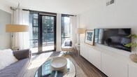 Located at 33 N St NE in Washington, DC, this contemporary single-floor residence showcases thoughtful design and high-quality finishes throughout. The open living area is bathed in natural light from floor-to-ceiling glass doors that lead to a private balcony, offering sweeping views of the surrounding cityscape. Rich hardwood flooring anchors the space, complementing the clean white walls and modern furnishings.

The kitchen is outfitted with stainless steel appliances, including a range, built-in microwave, and dishwasher, alongside sleek two-tone cabinetry — crisp white uppers paired with warm wood lowers — and a neutral tile backsplash that adds texture to the space.

The primary bedroom features a striking blue accent wall, large windows with balcony access, and ample natural light. A second bedroom offers deep charcoal-toned walls, a generous double-door closet, and soft carpeting for a cozy retreat. Both rooms provide a refined, restful atmosphere.

Two well-appointed bathrooms serve the residence. One features an open walk-in shower, dark wood vanity with open shelving, and large-format floor tile. The second includes a soaking tub with shower, an open-shelf vanity, and coordinating tile work. Together, these spaces deliver a cohesive, modern aesthetic in the heart of Washington, DC.