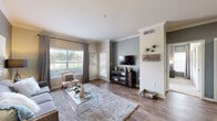 This single-floor residence offers a thoughtfully designed layout that balances comfort and style throughout. The open-concept living area is anchored by rich hardwood-style flooring, crown molding, and neutral gray accent walls that lend a contemporary feel. Large windows allow generous natural light to fill the space while offering views of the surrounding greenery, creating a bright and welcoming atmosphere.

The kitchen is equipped with dark espresso cabinetry, gleaming granite countertops, a stainless steel undermount sink with a modern faucet, and stainless steel appliances. An adjoining dining area provides an intimate space for meals, complemented by the same cohesive design palette.

The bedroom is carpeted and generously proportioned, featuring a ceiling fan, large windows, built-in shelving, and a dedicated desk nook — ideal for both rest and work. A spacious walk-in closet offers extensive wire shelving and hanging storage on multiple sides.

The bathroom features hardwood-style flooring, a dark vanity with ample counter space, and a full soaking tub with tiled surround accented by decorative tile insets. Crown molding and consistent finishes throughout tie the entire space together into a polished and livable home.