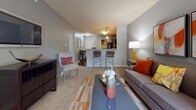 Located in Mechanicsville, Virginia, this single-floor residence at Hanover Crossings offers a thoughtfully designed open-concept layout that connects the living, dining, and kitchen areas seamlessly. The living room features soft carpet flooring, large sliding glass doors that open to a private patio with outdoor views, and generous wall space accented by warm, contemporary décor in tones of gray and orange.

The kitchen is equipped with dark espresso cabinetry, granite-style countertops, a full suite of black appliances including a refrigerator, range, microwave, and dishwasher, and a raised breakfast bar with pendant lighting — ideal for casual dining. Hardwood-style flooring adds warmth to the kitchen and dining area.

The primary bedroom is spacious and carpeted, featuring a large window with natural light, an upholstered headboard, and a dedicated closet with hanging storage. A second bedroom offers similar comfort with carpet, a bright window, and ample space. Both bathrooms are finished with dark vanity cabinetry, white countertops, hardwood-style flooring, and warm accent walls. A connecting hallway links the bedrooms and bathrooms cohesively. The overall design is consistent and modern throughout.