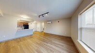 Located at 300 Broad Leaf Path in Mechanicville, NY, this thoughtfully designed one-bedroom, one-bathroom unit offers a functional and modern single-floor layout. The open-concept living and kitchen area creates a welcoming, airy atmosphere, with light-toned hardwood-style flooring extending seamlessly throughout the entire space. The living area is bathed in natural light through large windows and is equipped with track lighting overhead and a wall-mounted mini-split HVAC unit for year-round comfort. The kitchen is a standout feature, showcasing warm wood cabinetry, a marble-style countertop peninsula with a built-in sink, and black stainless appliances including a refrigerator, range, and microwave. The peninsula provides both additional prep space and a casual dining option. The bedroom offers a comfortable and private retreat, featuring dual closets with panel doors, a large window with exterior views, and its own wall-mounted HVAC unit. The full bathroom is clean and practical, with warm wood vanity cabinetry, a white countertop, a large mirror, and accessibility-ready grab bars. Neutral wall tones and consistent flooring throughout lend the space a cohesive, move-in-ready appeal.