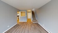 Located at 10435 Menard Ave in Oak Lawn, Illinois, this two-story residence offers a well-organized layout spread across two levels. The main living area welcomes you with warm wood-look laminate flooring, cool gray walls, and clean white trim throughout. A carpeted staircase connects the two floors, complemented by a pass-through window detail that adds architectural character between the living and kitchen areas. Sliding glass doors on the main level open to a private balcony, allowing natural light to fill the space and providing outdoor access.

The kitchen is efficiently designed with ample white cabinetry, white countertops, a stainless single-basin sink, and black appliances including a gas range, refrigerator, and dishwasher. Wood-look flooring continues into this space, creating a cohesive feel.

The bedrooms are carpeted and finished in soft gray tones, with windows offering natural light and views of the surrounding neighborhood. Generous walk-in closet space with built-in shelving and hanging rods provides practical storage solutions.

Two full bathrooms are present, each featuring a tub-shower combination with white tile surround, updated vanities with white countertops, and wood-look flooring. The consistent gray color palette and updated fixtures carry throughout both bathrooms, contributing to the home's clean, modern aesthetic.