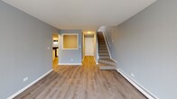 Located at 10435 Menard Ave in Oak Lawn, Illinois, this two-story residence offers a well-organized layout spread across two levels. The main living area welcomes you with warm wood-look laminate flooring, cool gray walls, and clean white trim throughout. A carpeted staircase connects the two floors, complemented by a pass-through window detail that adds architectural character between the living and kitchen areas. Sliding glass doors on the main level open to a private balcony, allowing natural light to fill the space and providing outdoor access.

The kitchen is efficiently designed with ample white cabinetry, white countertops, a stainless single-basin sink, and black appliances including a gas range, refrigerator, and dishwasher. Wood-look flooring continues into this space, creating a cohesive feel.

The bedrooms are carpeted and finished in soft gray tones, with windows offering natural light and views of the surrounding neighborhood. Generous walk-in closet space with built-in shelving and hanging rods provides practical storage solutions.

Two full bathrooms are present, each featuring a tub-shower combination with white tile surround, updated vanities with white countertops, and wood-look flooring. The consistent gray color palette and updated fixtures carry throughout both bathrooms, contributing to the home's clean, modern aesthetic.