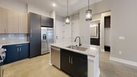Located at 146 Roberts St in Asheville, NC, this modern 2-bedroom, 2-bathroom unit delivers a clean, contemporary aesthetic across a well-planned single-floor layout. Polished concrete floors run throughout the entire space, lending an industrial-chic quality that ties each room together cohesively.

The open-concept kitchen serves as the functional centerpiece, featuring a granite-topped island with an undermount sink and stylish pendant lighting overhead. Dark lower cabinetry contrasts with lighter upper cabinets, complemented by a classic subway tile backsplash and a full suite of stainless steel appliances including a refrigerator, dishwasher, electric range, and microwave.

The living and dining area benefits from natural light streaming through large windows and glass-paned doors, creating a bright and welcoming atmosphere. Ceiling fans are present in the bedrooms and living areas for added comfort. Both bedrooms are generously proportioned, with the primary bedroom offering an en-suite bathroom and walk-in closet fitted with wire shelving systems. The second bedroom also enjoys ample natural light from dual windows.

Both bathrooms are finished with granite vanity countertops, dark cabinetry, and polished concrete floors. The full bath includes a tiled tub-shower combination. Additional features include three closets, an in-unit laundry area, and convenient access throughout the layout.