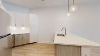 This well-appointed 1-bedroom, 1-bathroom unit offers a thoughtfully designed single-floor layout that maximizes every square foot. Light wood-tone flooring flows seamlessly throughout the space, complemented by crisp white walls and tall ceilings that create an open, airy ambiance. A standout design element is the recurring teal-painted interior doors, adding a bold and cohesive accent across rooms.

The modern kitchen features two-tone cabinetry with flat-front white upper cabinets and warm wood-grain lower cabinets, a white quartz peninsula with an undermount sink and brushed nickel faucet, and stylish glass pendant lights with gold hardware. A subway tile backsplash adds a clean, classic finish.

The living area is bright and open, benefiting from natural light through large windows and French doors, and is equipped with a ceiling fan. The bedroom is a comfortable size, with tall ceilings, natural light, and direct access to both a walk-in closet outfitted with wire shelving systems and the full bathroom.

The bathroom offers large-format tile flooring, a soaking tub with floor-to-ceiling marble-look tile surround, and a wood-accented vanity. A hallway and dedicated closet space complete this clean, modern unit.