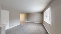 Located at 1553 Parkline Dr in Pittsburgh, PA, this multi-story home spans three floors and offers five bedrooms, one full bathroom, and a basement. Each floor carries a comparable footprint, providing a well-distributed layout throughout the home. The main level welcomes visitors through a windowed front door into a generously sized living area with soft carpet flooring, neutral taupe walls, and a large window that fills the space with natural light and neighborhood views. The kitchen features updated gray shaker-style cabinetry, granite-look countertops with a stainless steel sink, a tile backsplash, wood-look vinyl flooring, and black appliances including a range and refrigerator. The five bedrooms are carpeted and finished in neutral tones, with the spacious primary bedroom offering ample room and natural light through blinds-fitted windows. The full bathroom is cleanly appointed with white tile surround, a shower/tub combination, vanity, and a small window. Staircases connect each level efficiently. The unfinished basement, with painted cinder block walls and a concrete floor, presents significant potential for storage or future buildout. Overall, the home offers a practical and functional layout suited for a variety of living arrangements.