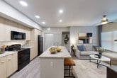Located in Houston, TX, this well-appointed 2-bedroom, 2-bathroom residence offers a thoughtfully designed single-floor layout with modern finishes throughout. The open-concept kitchen, dining, and living area serves as the heart of the home, anchored by a striking marble-look granite kitchen island with bar seating. Light wood cabinetry, black appliances, and wood-look plank flooring carry a clean, contemporary aesthetic throughout the space. Recessed lighting illuminates the combined living area, which flows seamlessly into a dedicated dining space featuring a built-in shelving nook ideal for a home office setup. The primary bedroom is a comfortable retreat with its own en-suite bathroom, complete with a granite vanity and light wood cabinetry. A second full bathroom includes a tiled tub-shower combination and additional overhead storage. The second bedroom features natural light from multiple windows and ample space for flexible use. Three closets provide generous storage, including a walk-in with floor-to-ceiling wire shelving systems. A dedicated laundry area with an in-unit washer adds everyday convenience. Neutral gray tones and consistent flooring throughout create a cohesive, move-in-ready living environment.