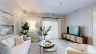 This single-story, 3-bedroom, 2-bathroom residence offers a bright and modern living experience with a thoughtfully designed open-concept layout. The living room serves as the heart of the home, featuring light wood-style flooring, neutral wall tones, and a sliding glass door framed by floor-to-ceiling sheer curtains that invite generous natural light and outdoor views. The kitchen is equipped with stainless steel appliances, granite-style countertops, sleek gray cabinetry, and a breakfast bar with seating — ideal for casual dining or entertaining. The primary bedroom is a comfortable retreat, highlighted by large windows with horizontal blinds and sheer drapes that filter natural light softly throughout the room. A dedicated closet with full-length hanging rods provides ample storage. Both bathrooms feature wood-look tile flooring, gray vanities with light stone countertops, and tub-shower combinations. A dedicated laundry room includes a full-size side-by-side washer and dryer. A connecting hallway ties the spaces together efficiently. Consistent use of light gray walls, wood-tone flooring, and clean white trim throughout creates a cohesive, contemporary aesthetic that feels both functional and welcoming.