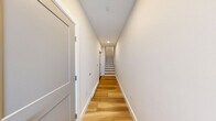 Located at 323 Taughannock Blvd in Ithaca, NY, this modern three-story home offers 2 bedrooms and 3 bathrooms thoughtfully distributed across its floors. Light-toned hardwood flooring runs throughout the living spaces, creating a cohesive, contemporary aesthetic complemented by neutral warm-white walls and abundant natural light.

The main living floor serves as the heart of the home, featuring a well-appointed kitchen with crisp white shaker cabinetry, stainless steel appliances, a subway tile backsplash, and a central island with a contrasting countertop and pendant lighting — ideal for both cooking and casual entertaining. The open layout connects seamlessly to the surrounding living areas.

The two generously sized bedrooms each feature ceiling fans, wide-panel windows that invite natural light, and easy access to outdoor views. The spacious primary bedroom offers a particularly comfortable retreat, complete with a closet featuring stylish blue-gray double doors. Waterfront views visible from bedroom windows add a distinctive character tied to the home's prime boulevard location.

The three bathrooms are finished with clean tile flooring, white subway-tiled tub surrounds, and blue-gray vanities with modern fixtures. Multiple staircases connect the floors efficiently, with open railings adding an airy architectural touch. The overall ambiance is fresh, modern, and move-in ready.