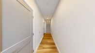 Located at 323 Taughannock Blvd in Ithaca, NY, this modern three-story home offers 2 bedrooms and 3 bathrooms thoughtfully distributed across its floors. Light-toned hardwood flooring runs throughout the living spaces, creating a cohesive, contemporary aesthetic complemented by neutral warm-white walls and abundant natural light.

The main living floor serves as the heart of the home, featuring a well-appointed kitchen with crisp white shaker cabinetry, stainless steel appliances, a subway tile backsplash, and a central island with a contrasting countertop and pendant lighting — ideal for both cooking and casual entertaining. The open layout connects seamlessly to the surrounding living areas.

The two generously sized bedrooms each feature ceiling fans, wide-panel windows that invite natural light, and easy access to outdoor views. The spacious primary bedroom offers a particularly comfortable retreat, complete with a closet featuring stylish blue-gray double doors. Waterfront views visible from bedroom windows add a distinctive character tied to the home's prime boulevard location.

The three bathrooms are finished with clean tile flooring, white subway-tiled tub surrounds, and blue-gray vanities with modern fixtures. Multiple staircases connect the floors efficiently, with open railings adding an airy architectural touch. The overall ambiance is fresh, modern, and move-in ready.