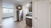 This single-floor residence offers a clean, modern aesthetic with thoughtfully updated finishes throughout. The kitchen is a standout feature, equipped with a full suite of stainless steel appliances including a gas range, over-the-range microwave, dishwasher, and refrigerator. Dark espresso cabinetry pairs elegantly with light countertops and a teal subway tile backsplash, creating a stylish and functional cooking space. Durable hardwood-style flooring runs through the kitchen and select rooms, complementing the neutral gray palette found throughout the home.

Multiple rooms provide versatile living and sleeping arrangements. Carpeted bedrooms feature ceiling fans with lighting and natural light from double-pane windows with blinds. Additional rooms finished with wood-look luxury vinyl plank flooring offer recessed lighting, wall-mounted air conditioning units, and double-door closets for ample storage. The bathroom is outfitted with tile flooring, a white vanity, and clean, functional fixtures.

The overall ambiance is bright, neutral, and move-in ready, with consistent white trim work and baseboards tying each room together cohesively. This space is well-suited for comfortable everyday living with a practical and contemporary design sensibility.