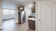 This single-floor residence offers a clean, modern aesthetic with thoughtfully updated finishes throughout. The kitchen is a standout feature, equipped with a full suite of stainless steel appliances including a gas range, over-the-range microwave, dishwasher, and refrigerator. Dark espresso cabinetry pairs elegantly with light countertops and a teal subway tile backsplash, creating a stylish and functional cooking space. Durable hardwood-style flooring runs through the kitchen and select rooms, complementing the neutral gray palette found throughout the home.

Multiple rooms provide versatile living and sleeping arrangements. Carpeted bedrooms feature ceiling fans with lighting and natural light from double-pane windows with blinds. Additional rooms finished with wood-look luxury vinyl plank flooring offer recessed lighting, wall-mounted air conditioning units, and double-door closets for ample storage. The bathroom is outfitted with tile flooring, a white vanity, and clean, functional fixtures.

The overall ambiance is bright, neutral, and move-in ready, with consistent white trim work and baseboards tying each room together cohesively. This space is well-suited for comfortable everyday living with a practical and contemporary design sensibility.