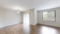 This two-bedroom, two-bathroom two-story home in Edgewater, NJ offers a well-designed layout spread across two floors. Rich, dark hardwood flooring flows throughout the main living areas, complemented by neutral-toned walls that create a clean and versatile aesthetic. The entry level welcomes you with a hallway leading into a spacious living room filled with natural light from large windows. A classic white staircase with elegant balusters connects the two floors seamlessly.

The galley-style kitchen is well-appointed with warm wood cabinetry, granite countertops, stainless steel appliances including a refrigerator, gas range, microwave, and dishwasher, and crisp tile flooring. It opens toward the bright living area, making the space feel connected and functional.

Upstairs, the generously sized primary bedroom features hardwood floors and a large window with outdoor views, providing a tranquil retreat. The second bedroom offers similar warmth and natural light. Both bathrooms are finished with clean white tile and include a round mirror vanity accent. A dedicated closet adds practical storage. The overall ambiance is bright, clean, and move-in ready, ideal for comfortable everyday living.