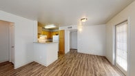 This single-story unit in McAllen, Texas offers a practical and comfortable layout designed for everyday living. The open living area serves as the heart of the space, featuring durable wood-look flooring, neutral walls, and a ceiling fan with light fixture. A glazed front door and a side window with blinds allow natural light to fill the room, creating a bright and welcoming atmosphere.

The kitchen is positioned adjacent to the living area and separated by a peninsula countertop, providing a functional workspace and an informal breakfast bar. Warm honey-toned wood cabinetry lines the walls, complemented by laminate countertops, a gas range, a white refrigerator, a stainless steel sink, and an overhead range hood. The wood-look flooring continues seamlessly from the living area into the kitchen.

A hallway leads to the private areas of the unit. The bedroom features plush carpet flooring, a ceiling fan, and a window with blinds that admits natural light. A second room, finished with the same wood-look flooring as the living spaces, also includes a ceiling fan and two windows. The bathroom is equipped with a shower-tub combination, a toilet, a vanity with laminate countertop, and wood-look flooring, completing a clean and functional layout throughout.