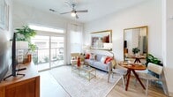 This single-story residence in Round Rock, Texas, presents a clean, contemporary design characterized by crisp white walls, light wood-style flooring, and an open, airy layout. The living area is generously proportioned, anchored by large windows and a sliding glass door that opens to a private balcony, allowing abundant natural light to fill the space. A ceiling fan adds comfort, while the seamless flow between the living and dining areas supports everyday functionality.

The kitchen is well-appointed with gray shaker-style cabinetry, granite countertops, a herringbone tile backsplash, stainless steel appliances including a side-by-side refrigerator, and a large island with an undermount sink. Recessed lighting enhances the workspace throughout. Adjacent to the kitchen, a built-in open shelving nook provides convenient organizational storage.

The bedrooms offer a calm retreat with plush carpet, ample natural light, and closets with built-in shelving and hanging rods. The bathroom features an extended dual-sink vanity with granite countertops, gray cabinetry, a tub-shower combination with tile surround, and wood-style flooring. The overall ambiance is modern, bright, and cohesive throughout.
