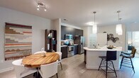 Located at 1420 Legacy Falls Dr in Wake Forest, NC, this single-floor residence offers a thoughtfully designed layout with modern finishes throughout. The open-concept kitchen and dining area serves as the heart of the home, featuring dark espresso cabinetry that extends to the ceiling, stainless steel appliances including a range, microwave, and French door refrigerator, and a curved white quartz peninsula with bar seating. A round wood dining table with white chairs completes the space, creating an inviting area for meals and entertaining. The living room is bright and welcoming, with a ceiling fan, large windows with outdoor views, and a glass door leading to a private balcony. Light wood-style flooring flows throughout the main living areas, adding warmth and continuity. The primary bedroom features plush carpeting, a ceiling fan, a natural light-filled window, and access to a spacious en-suite bathroom with a double-sink vanity, dark cabinetry, and a generous walk-in closet with wire shelving. The secondary bedroom is equally comfortable, offering carpet flooring and ample natural light. A secondary full bathroom provides a tub-shower combination and a single-sink vanity with coordinating dark cabinetry. The overall aesthetic is clean, contemporary, and move-in ready.