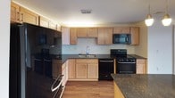 This single-floor residence offers a thoughtfully designed layout with a cohesive aesthetic throughout. Rich hardwood-style flooring flows through the main living areas and bedrooms, providing a warm, unified look. The spacious living area is anchored by elegant French doors topped with a transom window, allowing natural light to pour in while offering access to an outdoor balcony and views of the surrounding streetscape.

The kitchen is well-equipped for everyday living, featuring light wood cabinetry extending to the ceiling for ample storage, dark granite countertops, a subway tile backsplash, a double stainless steel sink, and black appliances including a refrigerator, range, and microwave. A peninsula provides additional counter space and casual seating.

Two generously sized bedrooms each feature hardwood-style flooring, ceiling fans with integrated lighting, and large windows with exterior views. The primary bedroom benefits from a walk-in closet outfitted with multi-level white wire shelving for efficient organization.

Two bathrooms serve the unit, each finished with neutral tile flooring and clean white fixtures. One includes a vanity with a wide mirror, while both offer tub-shower combinations. A wide central hallway connects the rooms, contributing to the unit's open and navigable flow.