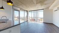 Located in Milwaukee's vibrant East Side neighborhood, this contemporary unit at 1943 N Summit Ave showcases an industrial-modern aesthetic defined by exposed concrete ceilings, structural concrete columns, and rich dark hardwood flooring throughout. The open-concept living area is bathed in natural light, courtesy of expansive floor-to-ceiling windows and glass doors that frame stunning panoramic views of Lake Michigan and the surrounding cityscape, with access to a private balcony. The kitchen is well-appointed with stainless steel appliances, granite countertops, white cabinetry with subway tile backsplash, and stylish pendant lighting — all set beneath the signature exposed concrete ceiling. The bedrooms offer hardwood flooring, generous windows with lake and city views, and a prominent concrete column that reinforces the unit's industrial character. Storage is handled by a large walk-in closet with built-in shelving and drawers. Both bathrooms feature granite-topped vanities, wood-look flooring, and clean, modern finishes. A stacked in-unit washer and dryer adds everyday convenience. A wall-mounted mini-split system provides efficient climate control, completing this thoughtfully designed urban residence.