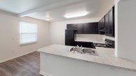 Located at 5313 Fairfield Rd in Columbia, South Carolina, this single-floor home offers a well-organized and functional layout designed for comfortable everyday living. The open-concept living and kitchen area serves as the heart of the home, where rich dark cabinetry provides striking contrast against light countertops and neutral walls. The kitchen is fully equipped with black appliances, including a full-size refrigerator and an electric range, complemented by ample upper and lower cabinet storage. A peninsula island with a double stainless steel sink adds both workspace and a natural divider between the kitchen and the living area. The flooring throughout the main living space features durable wood-style planks that lend a warm, contemporary feel. The bedrooms are carpeted for added comfort and each includes a ceiling fan with a light fixture and a window fitted with blinds, allowing for natural light while maintaining privacy. The bathroom is clean and straightforward, featuring a full-size soaking tub and shower combination with a white surround and chrome fixtures. Throughout the home, the neutral color palette and simple design elements create a bright, cohesive ambiance that is easy to personalize.