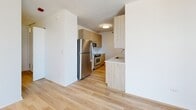 Located at 520 N Kingsbury Street in Chicago's vibrant River North neighborhood, this efficiently designed single-floor unit offers a thoughtfully arranged layout that maximizes every square foot. Light-toned hardwood flooring runs throughout the main living areas, creating a warm and cohesive aesthetic that complements the bright white walls.

The kitchen is a standout feature, outfitted with contemporary flat-front cabinetry in a natural wood finish, a crisp white countertop, and a subway tile backsplash. Stainless steel appliances — including a full-size refrigerator, range, and microwave — provide modern functionality, while ample upper and lower cabinet storage keeps the space organized.

The bathroom is finished with large-format, neutral-toned floor tiles and clean white walls, offering a minimalist and accessible design complete with grab bars for added convenience. Two closets provide generous storage options — one features floor-to-ceiling bi-fold white panel doors for a sleek, seamless look, while the other is equipped with wire shelving for versatile organization.

Natural light filters into the living area through a glass door that opens to an outdoor space, enhancing the airy, open feel of the interior. The textured white ceilings add subtle visual depth throughout. Overall, the unit presents a clean, modern aesthetic well-suited to urban living in one of Chicago's most sought-after neighborhoods.