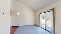 Located at 4400 E Busby Dr in Sierra Vista, Arizona, this one-bedroom, one-bathroom unit offers a efficiently designed single-floor layout. The living area is highlighted by soaring vaulted ceilings that create a sense of openness well beyond the unit's compact footprint. Soft carpeting runs throughout the living and bedroom spaces, while a sliding glass door opens onto a private balcony with views of surrounding greenery and neighboring architecture — bringing in abundant natural light. A wall sconce adds a subtle decorative touch to the bright, neutral-toned living space. The bedroom is a comfortable, well-proportioned room featuring a large window that frames sunny Arizona skies and views of the community. It connects directly to the full bathroom, which includes a clean, white-tiled tub-shower combination with chrome fixtures and a vanity with warm wood cabinetry. The kitchen is laid out in a galley style, featuring light wood cabinetry, a double-basin sink, a dishwasher, and a full-size refrigerator, all set atop rich hardwood-style flooring. A textured ceiling and overhead lighting complete the functional kitchen space. This unit offers a straightforward, practical living environment in a well-established Sierra Vista community.