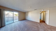 This two-bedroom, one-bathroom residence in Rohnert Park, California offers a practical and comfortable single-floor layout. The living room serves as the heart of the home, featuring plush wall-to-wall carpeting, warm neutral-toned walls, and a textured ceiling. A sliding glass door opens directly to a private balcony, filling the space with natural light and providing outdoor views. The galley-style kitchen is efficiently designed with white cabinetry lining both sides, light tile flooring, a full suite of white appliances including a refrigerator and range, and ample counter space for meal preparation. Both bedrooms are carpeted and finished with the same neutral palette, creating a calm and cohesive atmosphere. The primary bedroom is generously sized, while the second bedroom features a large window with vertical blinds that invite natural light. Three closets throughout the unit offer practical storage solutions. The full bathroom is clean and functional, featuring a tiled floor, a full tub-and-shower combination with built-in shelving, and a crisp white finish. A connecting hallway ties all rooms together, completing this well-organized and move-in-ready home.