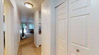 This single-floor residence offers a thoughtfully designed layout that balances comfort and functionality. The entryway, finished with tile flooring, leads into the heart of the home, where the living and dining areas connect seamlessly. The living room is carpeted and bathed in natural light from large windows with vertical blinds that offer views of lush greenery outside, creating a bright and welcoming atmosphere. A sliding glass door further enhances the connection to the outdoors.

The dining area features plush carpet, an elegant chandelier overhead, and a pass-through opening to the kitchen, making it ideal for both casual meals and entertaining. The kitchen is well-equipped with stainless steel appliances, white shaker-style cabinetry, granite-style countertops, and tile flooring, offering both style and practicality.

The two bedrooms are carpeted and include sliding closet doors, providing ample storage. Each room is generously proportioned with clean, neutral walls that allow for personalized décor. The hallway leads to two bathrooms, each featuring tile floors, vanities with granite-style countertops, and bright overhead lighting, ensuring convenience for residents and guests alike. Overall, the space presents a clean, cohesive aesthetic throughout.
