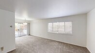 Located at 1812 W Riverside Ave in Spokane, Washington, this one-bedroom, one-bathroom unit offers a practical and well-organized single-floor layout. The open-concept living, dining, and kitchen area serves as the heart of the unit, with neutral-toned carpet underfoot and bright white walls that create a clean, airy atmosphere. A pendant light fixture adds a subtle decorative touch, while a sliding glass door leads directly to a private patio, allowing natural light to flow in and providing outdoor access. Multiple windows fitted with white horizontal blinds further brighten the space throughout. The bedroom is a comfortable, carpeted room featuring a built-in wall heater, a well-sized window for natural light, and access to a dedicated closet. The bathroom offers wood-look flooring and a white vanity with ample cabinet storage beneath a large mirror. Brushed nickel fixtures, including a towel bar and ring, lend a polished finish. A hallway connects the main living area to the private quarters, contributing to a functional flow throughout the unit. The overall design is straightforward and neutral, offering a versatile canvas well-suited to a range of interior styles.