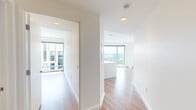Located on the 13th floor at 1335 Boylston Street in Boston's vibrant Fenway neighborhood, this two-bedroom, two-bathroom residence offers a thoughtfully designed open-concept layout finished with warm hardwood flooring and crisp white walls throughout. The combined kitchen and living area serves as the heart of the unit, featuring a sleek, modern kitchen outfitted with high-gloss white cabinetry, stainless steel appliances, a center island with an integrated sink, and floor-to-ceiling windows that frame impressive views of the Boston skyline. The living area extends to a striking curved window wall, flooding the space with natural light and offering sweeping panoramic views of the city below. The generously sized primary bedroom benefits from large floor-to-ceiling windows with urban views, while both bathrooms are finished with warm-toned tile flooring, white floating vanities, illuminated mirrors, and glass-enclosed showers. A hallway connects the bedrooms to the main living areas, with a dedicated closet for additional storage. The unit's elevated position, contemporary design, and abundant natural light create a bright, airy ambiance that showcases the best of high-rise city living in Boston.