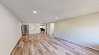 Located at 2401 S 25th St in Fort Pierce, Florida, this one-bedroom, one-bathroom unit offers a well-organized, single-floor layout designed to maximize every square foot. Light wood-look flooring runs continuously throughout the space, creating a cohesive and clean aesthetic. The open-concept living and kitchen area forms the heart of the unit, where recessed lighting illuminates white shaker-style cabinetry, a subway tile backsplash, and stainless steel appliances including a refrigerator and electric range. Neutral gray walls and a textured ceiling complement the bright, airy feel of the space. The living area is generously sized relative to the footprint, featuring a front-facing window and a dedicated entry door that allows natural light to filter in. A hallway connects the main living area to the private bedroom, which includes a ceiling fan with light fixture, a window overlooking the exterior, and a full-panel bi-fold closet for storage. The bathroom is efficiently laid out with a white vanity, mirror, toilet, and a full tub-shower combination. Clean finishes and consistent flooring tie the entire unit together, making this a practical and move-in ready space in Fort Pierce.