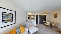 This 2-bedroom, 2-bathroom residence offers a thoughtfully designed single-floor layout that maximizes comfort and functionality. The open-concept living area serves as the heart of the home, featuring plush carpeting, neutral-toned walls, and a textured ceiling that adds subtle character to the space. A ceiling fan provides year-round comfort, while the layout allows for flexible furniture arrangements to suit a variety of lifestyles.

The kitchen is positioned just off the main living area and is defined by a peninsula counter that creates a natural division while maintaining an open, connected feel. Gray cabinetry, a classic subway tile backsplash, and black appliances give the kitchen a modern, polished look. The peninsula also provides convenient counter seating, making it ideal for casual dining or entertaining.

Adjacent to the kitchen, the dedicated dining area offers a cozy space for sit-down meals, seamlessly connected to the living room for easy flow between spaces. Dark-paneled storage or closet doors add a bold contrast to the lighter walls and flooring throughout.

With two full bedrooms and two bathrooms, this residence provides ample private space for residents or guests. The cohesive design, practical layout, and stylish finishes make this a well-rounded and inviting home.