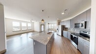 This well-appointed 2-bedroom, 2-bathroom residence offers a thoughtfully designed single-floor layout that maximizes both comfort and functionality. The open-concept living area seamlessly connects the kitchen, dining room, and living room, creating a bright and inviting atmosphere enhanced by abundant natural light from multiple windows. The modern kitchen is a standout feature, boasting a large granite-topped center island with an undermount sink, sleek gray cabinetry, a stylish geometric tile backsplash, stainless steel appliances, and elegant pendant lighting overhead. Wood-look flooring flows throughout the main living areas, adding warmth and continuity. The primary bedroom is generously sized and features plush carpeting, a ceiling fan, and a large walk-in closet with extensive built-in shelving and hanging rods. The second bedroom also offers carpeted floors, a ceiling fan, and a trio of windows that flood the room with natural light. Both bathrooms are finished with granite countertops and gray cabinetry, with one featuring a full tub and shower combo. Additional conveniences include three closets, a dedicated laundry area, a hallway, an entrance foyer, and access to a private balcony.