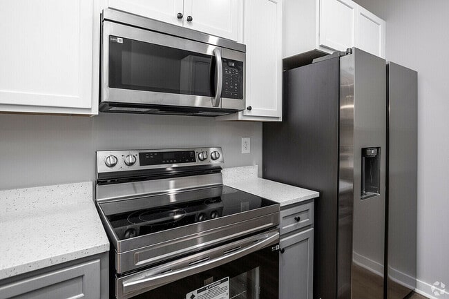 Experience the elegance of this modern kitchen equipped with high-end stainless steel appliances. - Woodford Ridge Townhomes