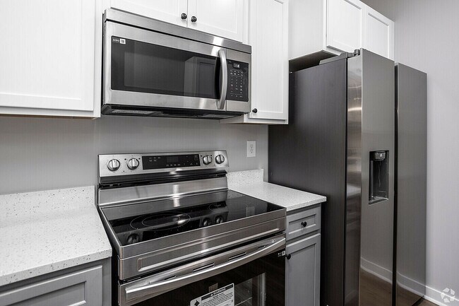 Experimente la elegancia de esta moderna cocina equipada con electrodomésticos de acero inoxidable de alta gama. - Woodford Ridge Townhomes