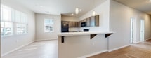 This single-story unit offers a well-organized layout with distinct living, kitchen, bedroom, and bathroom areas finished in a consistent, neutral palette throughout. The kitchen serves as a central feature, equipped with dark espresso-toned cabinetry that extends to the upper and lower sections of the walls, providing generous storage. Black appliances, including a refrigerator, range, and over-the-range microwave, complement the cabinetry. A peninsula with a white countertop and decorative bracket supports doubles as a breakfast bar, separated from the adjacent dining and living areas by a half-wall. Pendant lighting hangs above the peninsula, adding a functional yet stylish accent. Light wood-style flooring runs through the kitchen and living areas, offering easy maintenance and a clean aesthetic. Natural light enters through multiple windows fitted with horizontal blinds. The bedrooms feature plush carpeting, ceiling fans, and reach-in closets with double hanging rods and shelving. The bathrooms are finished with matching dark vanity cabinetry, white countertops, and a tub-shower combination with brushed nickel fixtures, all set on light wood-style flooring for a cohesive look.