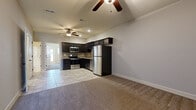 Located in Lee's Summit, Missouri, this two-story, three-bedroom, two-bathroom home offers a functional and well-designed layout spread across two floors. The main level features an open-concept living and kitchen area, where plush carpet in the living room transitions to tile flooring in the kitchen. The kitchen is appointed with dark espresso cabinetry, granite-look countertops, a mosaic tile backsplash, stainless steel appliances including a refrigerator, range, microwave, and dishwasher, and a built-in wine rack — all complemented by recessed lighting and a ceiling fan overhead. A hallway on the lower level connects to closet and utility spaces, with a staircase featuring classic wood balusters leading to the upper floor. The upper level houses the generously sized primary bedroom, which impresses with soaring vaulted ceilings, a ceiling fan, plush carpeting, and direct access to a private bathroom and a walk-in closet. The en-suite bathroom features dark vanity cabinetry with a white countertop and tile flooring. Two additional bedrooms on this level each offer carpet flooring, ceiling fans, and closet storage. A second full bathroom with a tub-shower combo and tile floors serves the remaining bedrooms. Throughout, neutral tones and clean finishes create a cohesive and inviting atmosphere.