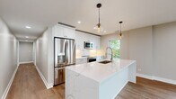 Located at 550 Sheridan Square in Evanston, IL, this well-appointed 3-bedroom, 2-bathroom residence offers a thoughtfully designed single-floor layout with modern finishes throughout. Wide-plank hardwood flooring flows seamlessly across the entire unit, lending warmth and continuity to every room.

The open-concept kitchen and living area serves as the heart of the home. The chef's kitchen is highlighted by a large waterfall-edge quartz island with an undermount sink, crisp white shaker cabinetry extending to the ceiling, stainless steel appliances, a decorative tile backsplash, and stylish globe pendant lights. The expansive living room features recessed lighting, large windows, and sliding glass doors that open directly onto a private balcony with views of lush greenery.

The generously sized primary bedroom offers a walk-in closet outfitted with custom shelving and hanging rods, providing ample storage. Additional bedrooms are well-proportioned, each with natural light from windows framing outdoor tree canopy and lake views. The two bathrooms are finished with clean, contemporary tile work, including a soaking tub with textured white tile surround. A dedicated utility room and closet round out the functional layout, making this a complete and livable residence in a desirable Evanston location.