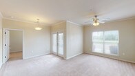 This 2-bedroom, 2-bathroom residence offers a thoughtfully designed single-level layout that balances comfort and functionality. The open living and dining area features plush neutral carpeting, crown molding, and ceiling fan lighting, with a large window and French doors that invite abundant natural light and outdoor views. A pendant light fixture above the dining space adds a refined touch to the open layout.

The galley-style kitchen is outfitted with dark espresso cabinetry, light granite-style countertops, a double stainless steel sink, and black appliances including a range and refrigerator. Rich wood-look flooring runs throughout the kitchen, creating a warm contrast against the cabinetry.

Both bedrooms are generously sized, each featuring soft carpeting, ceiling fans, and windows that allow natural light to fill the rooms. The neutral wall tones provide a versatile backdrop throughout.

The two bathrooms are finished with wood-look flooring, dark vanity cabinetry, and full tub-shower combinations with chrome fixtures. Each bathroom is clean and efficiently laid out. The overall design of this residence is cohesive and move-in ready, offering a practical and comfortable living environment.