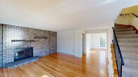 Located at 1727 Wedgewood Common in Concord, Massachusetts, this three-floor home offers a well-organized layout with consistent hardwood flooring and a clean, neutral palette throughout. The living room serves as a standout space, anchored by a full-wall exposed brick fireplace that adds significant architectural character. Large windows flood the room with natural light, and the warm-toned hardwood floors extend seamlessly into an adjacent room that features a glass door opening to the outdoors, enhancing the connection between interior and exterior spaces.

The kitchen is finished with white cabinetry, light countertops, and tile flooring, providing a bright and functional workspace. A dining or sitting area adjoins the kitchen, maintaining an open, cohesive flow on the main level. The floor plan model reveals a generously proportioned layout with multiple interconnected rooms across the level.

The upper level includes bedrooms with continued hardwood flooring and multiple closets offering ample storage. The bathroom is finished with white tile wainscoting, a tub-shower combination, and tile flooring. Additional rooms throughout the home provide flexible space for various uses. The overall ambiance is light, open, and well-maintained.
