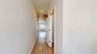 Located in the Champions Gate community of San Antonio, TX, this two-story home offers a thoughtfully designed layout spread across two floors. The main level features a spacious living room with light wood-look flooring, a ceiling fan, and a staircase with dark wood railings connecting to the upper level. The kitchen is a standout, equipped with tall gray cabinetry, a large center island with a white countertop, stainless steel appliances including a refrigerator, range, microwave, and dishwasher, and pendant lighting overhead. A hallway connects the main living areas and leads to the attached garage, which provides ample storage and parking space. Upstairs, three well-sized bedrooms feature plush carpeting, ceiling fans, and natural light from windows with blinds. The generously sized primary bedroom includes a walk-in closet with built-in shelving. Two additional closets offer extra storage throughout the home. All three bathrooms are finished with wood-look tile flooring, gray vanities, and tiled tub-shower combinations. The clean, neutral palette throughout creates a bright and welcoming atmosphere, making this home a comfortable and practical residence in San Antonio.