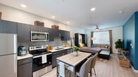 Located at 10000 West Missouri Avenue in Glendale, Arizona, this efficiently designed studio offers a thoughtfully arranged single-floor layout that maximizes every square foot. The open-concept living and kitchen area is anchored by a sleek, contemporary kitchen featuring dark espresso cabinetry, light quartz countertops, a gray tile backsplash, and a full suite of stainless steel appliances — including an electric range, over-the-range microwave, dishwasher, and refrigerator. Light wood-style flooring runs throughout, lending warmth and visual continuity to the space. Recessed lighting and a ceiling fan with light keep the living area bright and comfortable, while window blinds provide privacy and light control. A compact dining table with modern chairs sits between the kitchen and living area, making efficient use of the open floor plan. The bathroom is clean and well-appointed, featuring a full tub and shower combination, white vanity with an undermount sink, and light tile flooring. A dedicated laundry area houses a full-size stacked washer and dryer unit. The entry features a modern door with a keypad lock and a window that brings in natural light. This studio offers a functional, contemporary living space with quality finishes throughout.