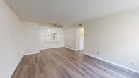 Located at 5675 Barnhill Dr in Jacksonville, FL, this single-floor unit offers three bedrooms and two bathrooms within a thoughtfully arranged floor plan. The combined living and dining area serves as the heart of the home, finished with warm wood-look laminate flooring that extends throughout the unit. A ceiling fan with light fixture keeps the space comfortable, while a pass-through window connects the living area directly to the kitchen, creating an open, communicative feel. The kitchen features white cabinetry and includes a refrigerator, maintaining a clean and functional aesthetic. Bedrooms are bright and well-proportioned, each featuring the same wood-look flooring, neutral cream-toned walls, and vertical blind-covered windows that invite natural light. Several bedrooms include closets, and the unit provides a total of four closets for generous storage throughout. The two bathrooms are finished in a crisp white palette — one features a full tub and shower with white subway tile surround and a white vanity, while the second offers a single vanity with mirror and tile flooring. Textured ceilings and clean white trim complete the interior. The layout, as seen in the dollhouse view, is efficiently organized with clear room separation and easy flow between spaces.