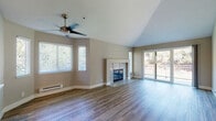 Located at 962 Old Quarry Rd S in the charming town of Larkspur, California, this single-floor residence offers a thoughtfully designed layout with a bright, open atmosphere throughout. The expansive living room immediately impresses with its soaring vaulted ceilings and a ceiling fan that enhances airflow and comfort. A tile-surround fireplace serves as the room's focal point, while wide-plank hardwood-style flooring extends underfoot. Multiple windows fitted with blinds invite abundant natural light, and sliding glass doors open directly onto a private balcony with leafy outdoor views. The open-concept design connects the living area to the kitchen, which features rich dark-wood cabinetry, white countertops, stainless steel appliances including a range and microwave, and a double basin sink beneath a window. Bedroom spaces are carpeted for comfort and include baseboard heating and natural light from well-placed windows. The bathrooms are clean and functional, each offering a tub-shower combo, a single vanity with white countertop, and dark wood cabinetry consistent with the home's design palette. An in-unit laundry area accommodates a full-size washer and dryer, adding everyday convenience. The overall ambiance is airy, neutral, and move-in ready.