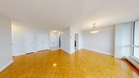 This 1-bedroom, 1-bathroom unit offers a clean, functional layout with consistent warm-toned parquet flooring throughout the main living areas and bedroom. The spacious living room is a standout feature, anchored by a wall of floor-to-ceiling windows that frame sweeping city and treetop views, flooding the space with abundant natural light. A pendant light fixture in the adjacent dining area adds a subtle decorative touch, while direct access to the kitchen keeps the layout practical and connected.

The kitchen is efficiently designed with white shaker-style cabinetry, granite-look countertops, a subway tile backsplash, and stainless steel appliances including a full-size refrigerator. Light ceramic tile flooring completes the kitchen's clean aesthetic.

The bedroom is a well-sized, quiet retreat featuring a double-door closet and its own baseboard heating unit, ensuring year-round comfort. Neutral grey walls and the same parquet flooring carry through from the main living areas.

The bathroom is finished with crisp white subway tile surrounding a full soaking tub with a sliding shower bar, providing a clean and timeless look. A hallway connecting the main rooms offers additional storage access. Overall, the unit presents a bright, cohesive, and move-in ready living space.