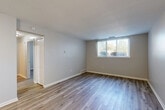 Located at 1551 Marie St in Trenton, Michigan, this one-bedroom, one-bathroom unit offers a clean, modern aesthetic across a single floor. Light wood-look plank flooring runs throughout, creating a cohesive and easy-to-maintain foundation across all living spaces. Neutral gray walls and crisp white trim complement the bright, airy atmosphere.

The open living room is a welcoming space, featuring a large window with vertical blinds that allows natural light to fill the room. The layout flows efficiently into the kitchen, which is accessible through an arched opening. The kitchen is outfitted with warm honey-toned wood cabinetry, granite-look countertops, a double stainless steel sink, and black appliances including a refrigerator and dishwasher.

A hallway connects the main living area to the bedroom and bathroom. The bedroom is a comfortable, well-proportioned space with its own window for natural light and a full closet with paneled double doors, offering generous storage. Two closets are available within the unit for added convenience.

The bathroom features a full soaking tub and shower combination with a clean white surround. The unit's practical layout, consistent finishes, and functional amenities make it a straightforward and inviting living space.