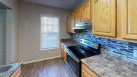 Located at 125–199 Arborside Dr in Augusta, Georgia, this single-floor residence offers a practical and comfortable layout with a neutral color palette throughout. The kitchen is well-appointed with warm honey-toned wood cabinetry, granite-look countertops, a stainless steel range, and a decorative tile backsplash, all complemented by wood-look vinyl flooring and a bright window that brings in natural light. A hallway connects the main living areas to the private quarters, with doors leading to additional rooms and closets. The spacious living area features plush carpeting and a textured ceiling, providing a comfortable, open feel. The bedrooms are generously sized, each finished with soft carpeting, ceiling fans with integrated lighting, and textured ceilings. One bedroom benefits from natural light through a window with blinds. A large walk-in closet offers extensive wire shelving and hanging space, ensuring ample storage. The bathroom is clean and functional, featuring a full tub-shower combination with a curtain rod, wood-look vinyl flooring, and simple, modern fixtures. Throughout the residence, consistent gray tones and white trim create a cohesive, move-in-ready aesthetic.
