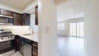 Located at 1000 US Highway 1 in Edison, NJ, this efficiently designed single-floor unit offers a thoughtful layout that maximizes every square foot. The open-plan kitchen and living area form the heart of the space, with light wood-tone flooring running throughout to create a cohesive, airy feel. The kitchen is well-appointed with rich dark espresso cabinetry, stainless steel appliances including a refrigerator, gas range, microwave, and dishwasher, complemented by a clean white quartz countertop and a stainless steel sink. A pass-through opening connects the kitchen to the living area, enhancing the open flow between spaces. The living area is bright and welcoming, benefiting from natural light streaming in through a large window and a sliding glass door that opens to an outdoor view, fitted with vertical blinds. The bathroom features a dark wood vanity with a white countertop, above-vanity storage cabinet, a glass-enclosed shower/tub combination, and light tile flooring that mirrors the clean aesthetic of the rest of the unit. A dedicated closet with built-in shelving provides practical storage. Neutral wall tones and consistent finishes throughout give the space a modern, move-in-ready appearance.