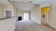 This single-floor residence offers a thoughtfully designed layout with a variety of functional and comfortable spaces throughout. The living room serves as the heart of the home, featuring a vaulted ceiling that enhances the sense of openness, a classic fireplace with a white mantle, and a sliding glass door leading to a private balcony that allows natural light to flow freely into the space. Neutral-toned carpet and warm beige walls create a calm, welcoming ambiance.

The kitchen is well-equipped with abundant white cabinetry, dark granite-style countertops, and warm hardwood flooring. White appliances including a range, built-in microwave, and refrigerator are complemented by generous counter space and a dedicated desk nook, making the kitchen as practical as it is attractive.

The dining area features crown molding, an elegant chandelier, and easy access to the entryway, offering a refined yet functional space for meals. The bedrooms are carpeted and generously proportioned, with one offering notably tall ceilings and direct access to the kitchen. A spacious walk-in closet with wire shelving provides ample storage.

The bathrooms are finished with wide vanities, white cabinetry, and large mirrors. One bathroom conveniently adjoins the in-unit laundry area, adding everyday practicality to the overall layout.