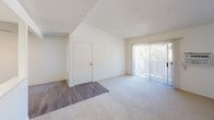 This single-floor unit offers a clean, functional layout with a bright and welcoming ambiance throughout. The living area serves as the central hub of the space, featuring a combination of wood-look and plush carpet flooring, a textured ceiling, and a large sliding glass door fitted with vertical blinds that invites natural light and provides outdoor access. An open pass-through connects the living area to the kitchen, which features white cabinetry, overhead lighting, and a breakfast bar-style counter that enhances the open feel of the shared space.

The bedrooms are carpeted and well-lit, each with windows dressed in vertical blinds that allow for natural light. The primary bedroom includes direct access to a dedicated en-suite bathroom area featuring a wide vanity with a speckle-finish countertop, a large mirror with strip lighting, and a private water closet. A second full bathroom is also present, equipped with a combined tub and shower unit, chrome fixtures, a toilet, and wood-look flooring, offering practical functionality for guests or additional occupants.

Throughout the unit, the neutral color palette of whites and warm beiges creates a clean, move-in-ready environment. The textured ceilings, consistent trim work, and thoughtful room transitions reflect a cohesive and practical design suited for everyday living.